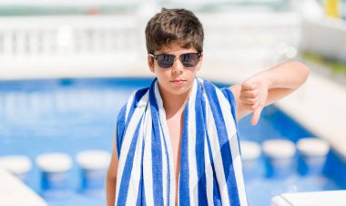 Kızgın yüz, eksi işareti aşağı antipati başparmak ile gösterilen, ret kavramı ile plajda yüzme havuzunda tatil günlerinde genç çocuk