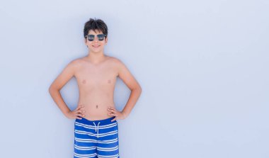 Bir gülen surat konumu olan duvar üzerinde duran ve diş gösterilen kendine güvenen bir gülümsemeyle gülümseyerek tatil günlerinde genç çocuk