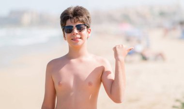 İşaret ve başparmak kadar mutlu yüz gülümseyen tarafı ile gösterilen sahilde tatil günlerinde genç çocuk