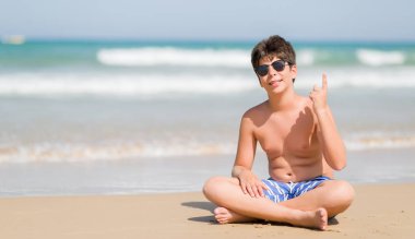 Plajda bir fikir ya da soru işaret parmağı ile gülen yüz, sürpriz tatil günlerinde genç çocuk bir numara