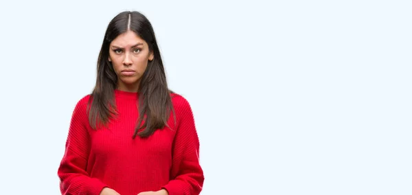 年轻漂亮的西班牙裔穿着红毛衣的人持怀疑态度 紧张不安 皱起眉头 消极的人 — 图库照片