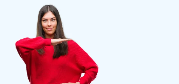 若い美しいヒスパニック系メジャー シンボル兆し大きな 大きなサイズの手で身振りで示す赤いセーターを着ています カメラを見て笑っています 測定概念 — ストック写真