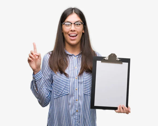 Mujer Hispana Joven Sosteniendo Portapapeles Sorprendida Con Una Idea Pregunta — Foto de Stock