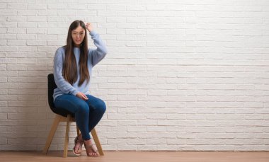 Sandalye üzerinde tuğla duvar rahatsız ve öfke, çılgın ve yükseltilmiş eliyle diye bağıran ile sinirli bağırarak öfke kavramı oturan genç Çinli kadın