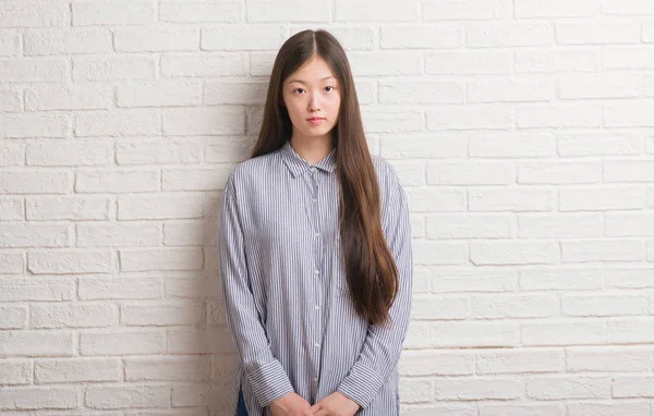 スマートの顔は深刻な思考に自信を持って表現でレンガの壁の上の若い中国の女性 — ストック写真