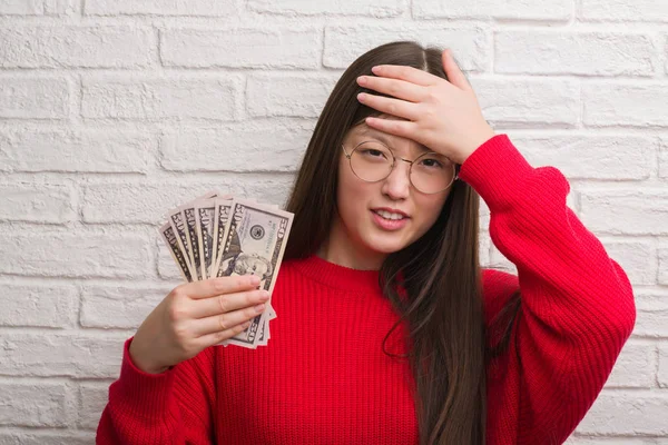Jovem Chinesa Sobre Parede Tijolo Segurando Dólares Estressado Com Mão — Fotografia de Stock