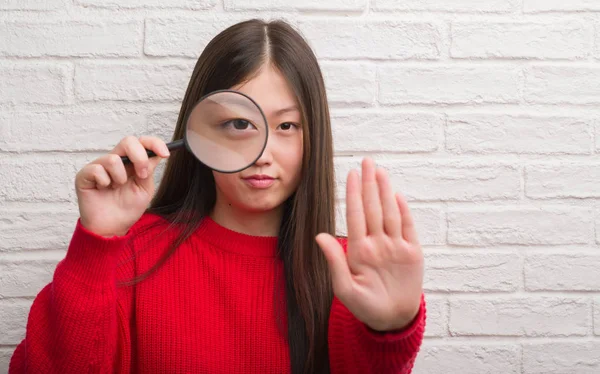 Young Chinese Woman Brick Wall Looking Magnifying Glass Open Hand — Stock Photo, Image