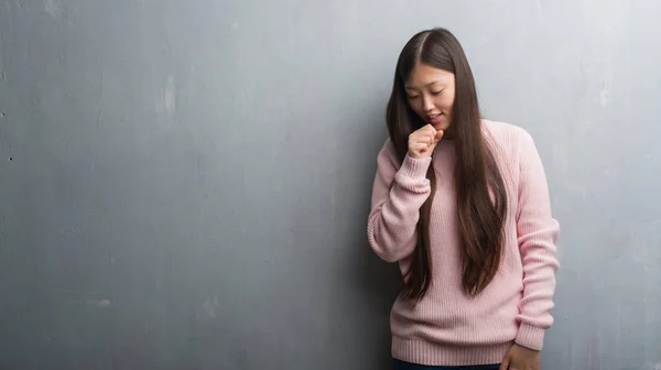 年轻的中国妇女在灰色墙壁感觉不适和咳嗽作为症状为感冒或支气管炎 医疗保健理念 — 图库照片