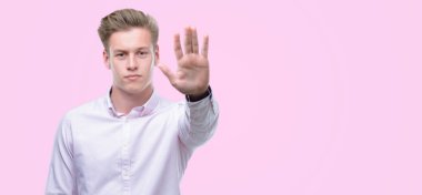 Genç yakışıklı sarışın adam açık eliyle dur işareti ile ciddi ve kendine güvenen ifade, savunma hareketi yapıyor