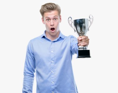 Genç yakışıklı sarışın adam bir kupa bir sürpriz yüz, korkuyor ve heyecanlı korku ifadesi ile şok korkmuş holding