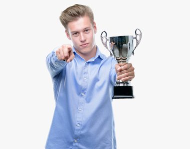 Genç yakışıklı sarışın adam kamera ve size, el işareti, pozitif ve kendinden emin bir jest ön parmak ile işaret bir kupa holding