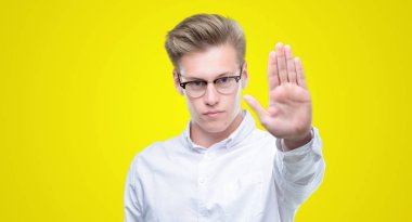 Elin avuç durağı şarkı yapan genç yakışıklı sarışın erkek. Negatif ve ciddi bir jest yüz ifadesiyle uyarı.