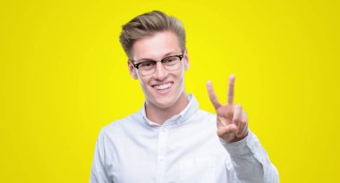 Zafer işareti yapıyor parmak gösterilen kamera seyir gülümseyen genç yakışıklı sarışın adam. İki numaralı.