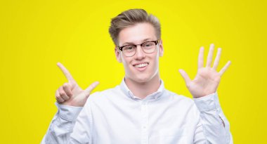 Gösterilen ve parmakları ile işaret genç yakışıklı sarışın adam kendinden emin ve mutlu gülümseyerek süre yedi numara.