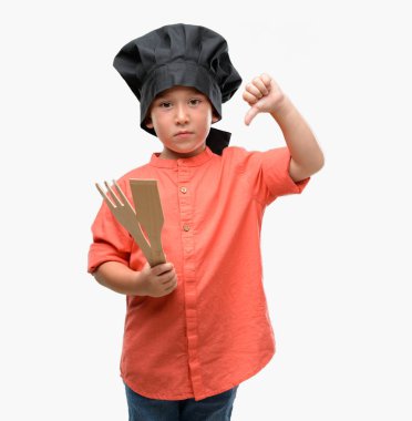 Koyu saçlı küçük çocuk şef üniforması kızgın yüzü, eksi işareti aşağı antipati başparmak ile gösterilen, ret kavramı ile