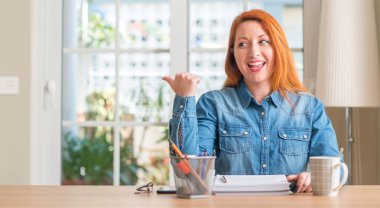 Kızıl saçlı kadın ev el ve parmak ile mutlu yüz gülümseyen ile yukarı dönük öğrenim