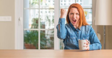 Bir fincan kahve rahatsız ve öfke, çılgın ve yükseltilmiş el, öfke kavramı ile diye bağıran ile sinirli bağırarak tutan Kızıl saçlı kadın