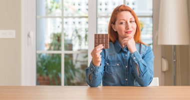 Soru, çok karışık fikir düşünmeye ev ciddi bir yüz, çikolata bar tutan Kızıl saçlı kadın