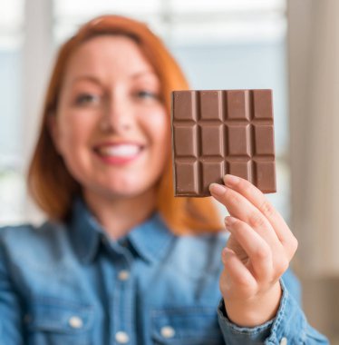 Gurur çığlık ve zafer ve başarı çok kutluyor evde çikolata bar tutan Kızıl saçlı kadın, duygu tezahürat heyecanlı