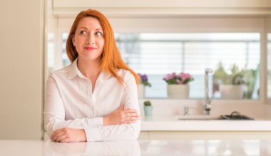 Kızıl saçlı kadın görünümlü yan ve dik dik bakma uzağa düşünce gülümseyen mutfak at.