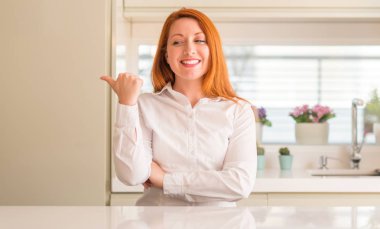 Kızıl saçlı kadına bakarak ve başparmak yanında yukarıyı mutlu yüz ile gülümseyen mutfak.