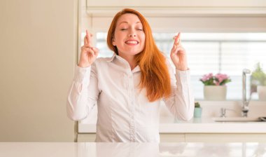 Kızıl saçlı kadına geçiş parmakları umut ve gözler gülümseyen mutfak kapalı. Şans ve batıl kavramı.