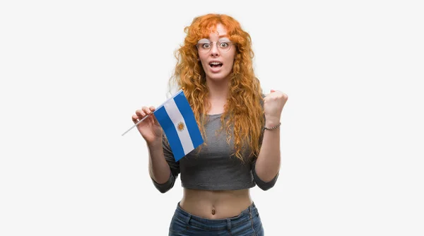 Młoda Ruda Kobieta Trzyma Flagę Argentyny Krzyczy Dumny Świętuje Zwycięstwo — Zdjęcie stockowe
