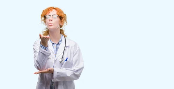 Young Redhead Woman Wearing Doctor Uniform Looking Camera Blowing Kiss — Stock Photo, Image