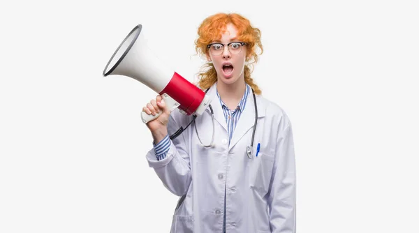 Młoda Ruda Kobieta Lekarz Trzymając Megafon Przestraszony Szoku Ścianą Niespodzianka — Zdjęcie stockowe