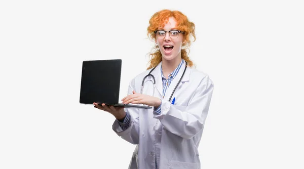 Young Redhead Doctor Woman Holding Computer Laptop Scared Shock Surprise — Stock Photo, Image