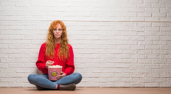 Unga Rödhårig Kvinna Sitter Över Tegelvägg Äta Popcorn Med Självsäker — Stockfoto