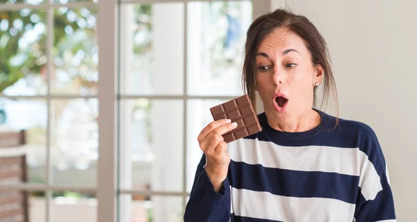 Mulher Meia Idade Comendo Chocolate Bar Assustado Choque Com Rosto — Fotografia de Stock