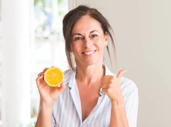 笑顔の サイン 優秀な兆候を親指をやって幸せなオレンジ色の果物を保持している中年の女性 — ストック写真