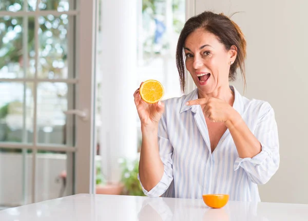 オレンジ色の果物を手と指で指している非常に満足して保持している中年の女性 — ストック写真
