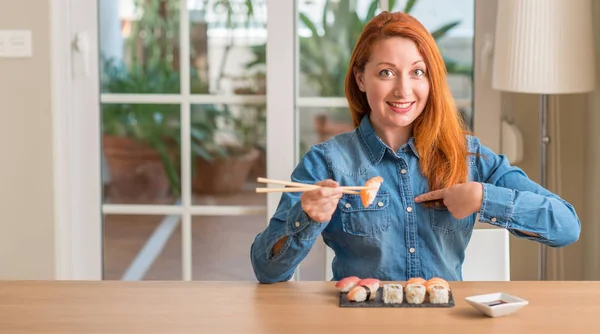 Redhead Woman Eating Sushi Using Chopsticks Surprise Face Pointing Finger — Stock Photo, Image