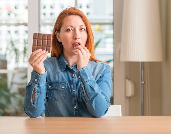 Mulher Ruiva Segurando Barra Chocolate Casa Com Uma Expressão Confiante — Fotografia de Stock