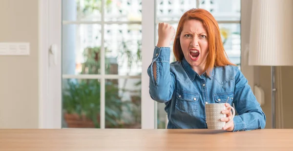 Rødhåret Kvinde Holder Kop Kaffe Irriteret Frustreret Råbe Med Vrede - Stock-foto