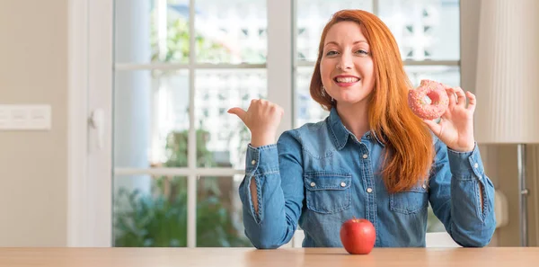 Rossa Donna Sceglie Tra Mela Ciambella Puntando Con Mano Dito — Foto Stock