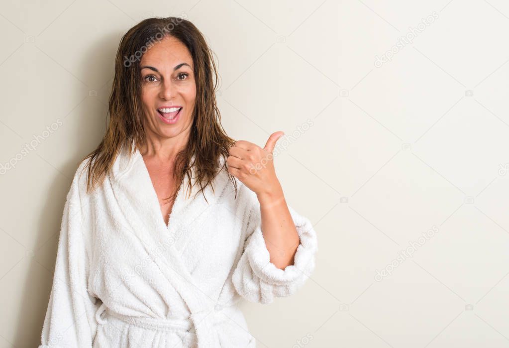 Beautiful middle age woman, wet hair wearing a towel pointing with hand and finger up with happy face smiling