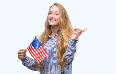 Amerika Birleşik Devletleri bayrağı çok mutlu el ve parmak ile tarafına işaret tutan sarışın genç kadın