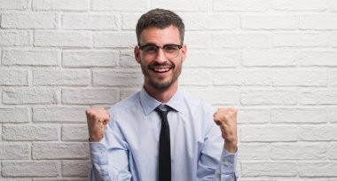 Genç Yetişkin iş adam gurur çığlık ve zafer ve başarı çok heyecanlı, kutluyor beyaz tuğla duvarı ayakta duygu tezahürat