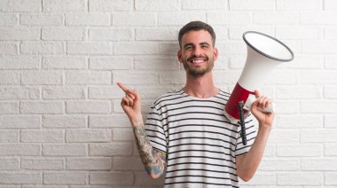 Megafon çok mutlu el ve parmak ile tarafına işaret tutan genç yetişkin adam