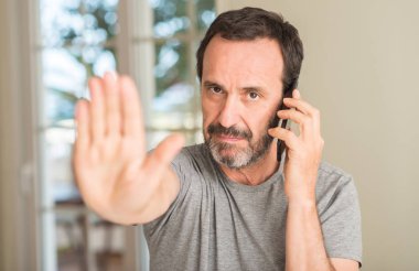 Açık eliyle dur işareti ile ciddi ve kendine güvenen ifade, savunma jest yapıyor Smartphone kullanarak orta yaş erkek