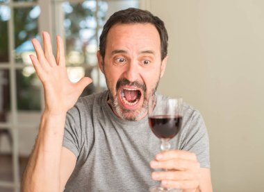 Kocaman bir gülümseme ile çığlık zaferini kutluyor ve ellerini kaldırdı şarap çok mutlu ve heyecanlı, kazanan ifade bir kadeh içmek orta yaş erkek