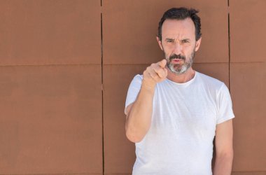 Üst düzey yakışıklı kamera ve size, el işareti, pozitif ve kendinden emin bir jest ön parmak ile işaret duvarın üzerinden ayakta