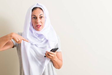 Arap kadın kendisine sürpriz yüz işaret parmağı ile Smartphone kullanarak