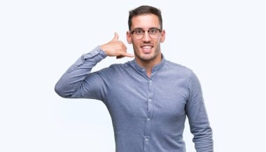 İşin gülümseyen gözlüklü zarif yakışıklı genç telefon hareketi ile el ve parmak telefonda konuşuyor gibi. Kavramları iletişim.