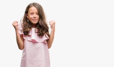 Esmer Latin kız kutlayan pembe elbise giyiyor şaşırttı ve başarı için kaldırdı kollarını açarak hayrete ve gözleri açık. Kazanan kavramı.