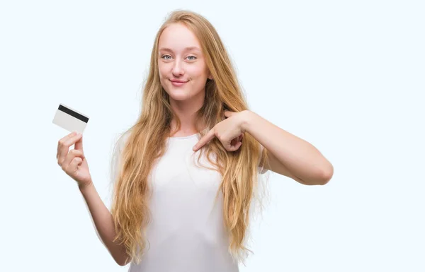 Blonde Teenagerin Hält Kreditkarte Mit Überraschendem Gesicht Und Zeigt Mit — Stockfoto