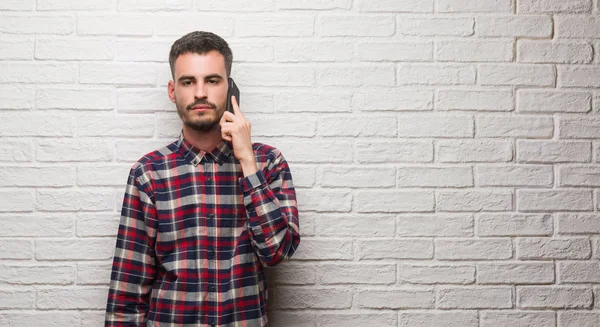 Νεαρός Ενήλικος Μιλώντας Για Τηλέφωνο Στέκεται Πάνω Από Λευκό Τοίχο — Φωτογραφία Αρχείου